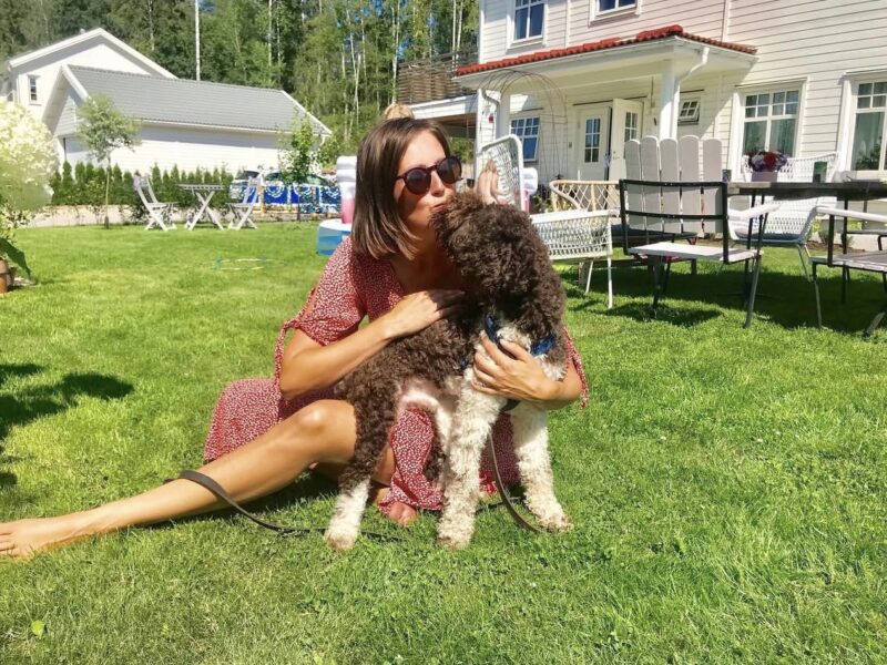 Woman in a garden receiving a kiss from her roan Lagotto Romagnolo.