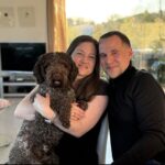 Family relaxing at home with their medium-sized brown Lagotto Romagnolo.