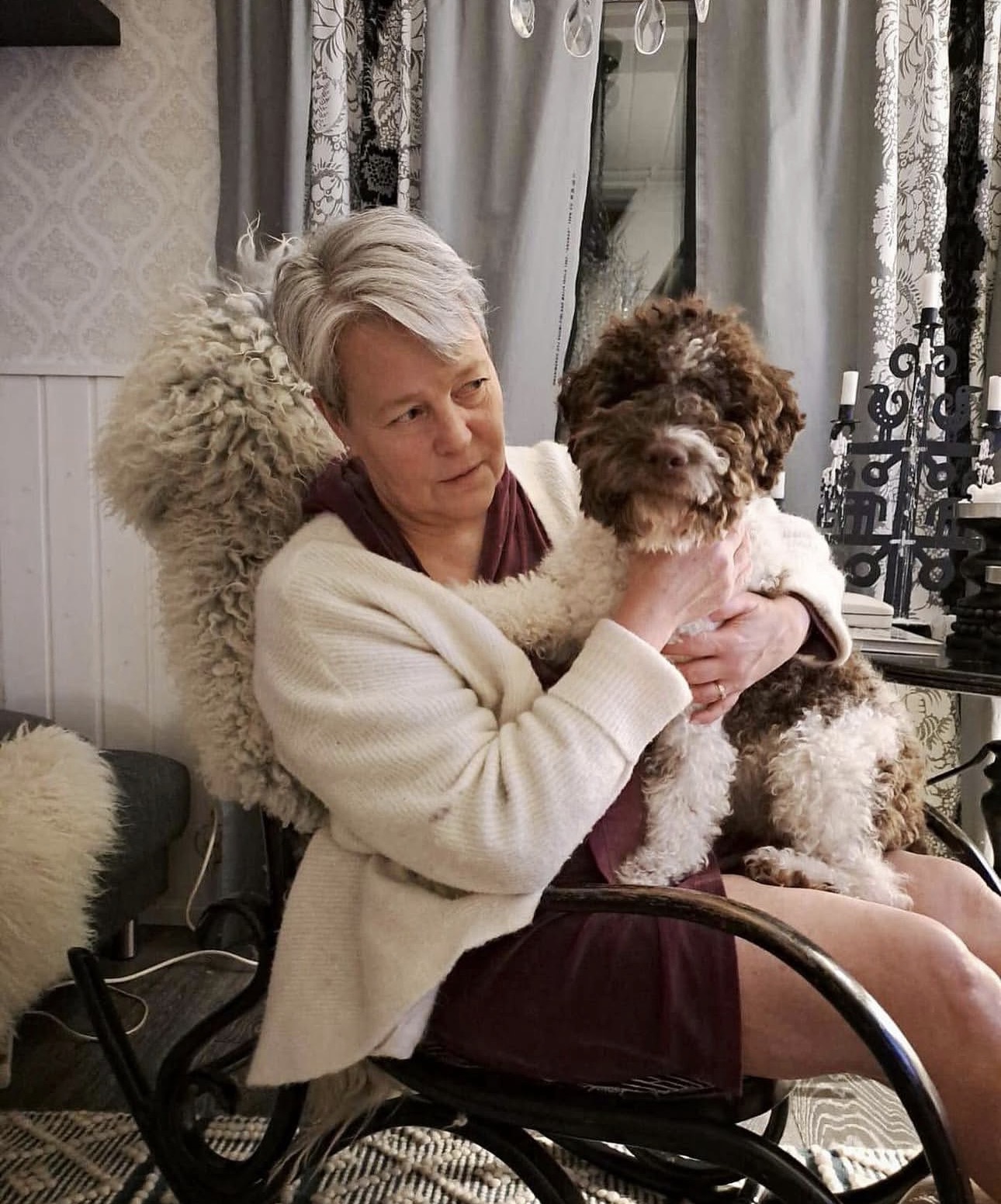 Senior woman bonding with a white and brown roan Lagotto Romagnolo puppy.