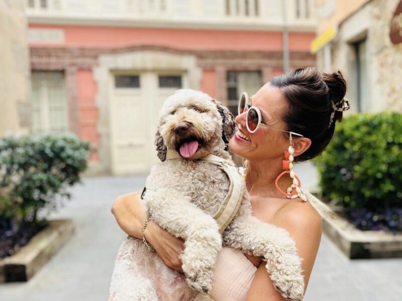 Stylish woman carrying her light brown Lagotto Romagnolo through a European town.