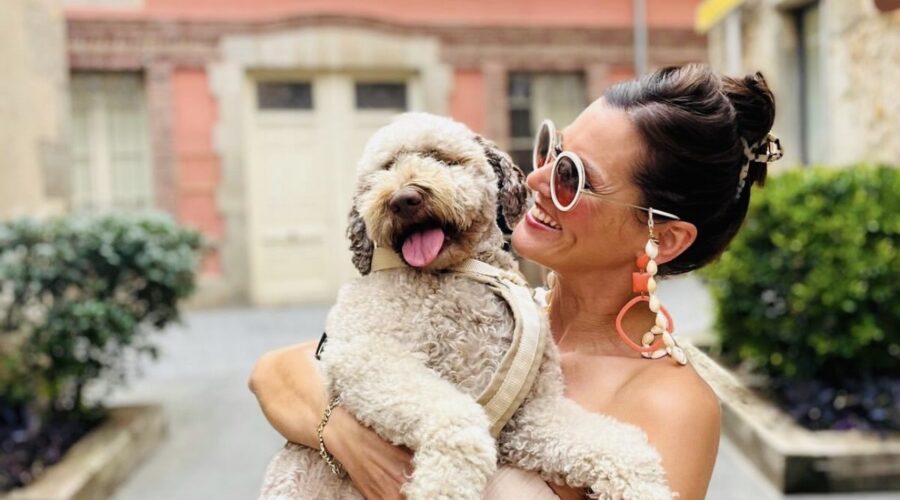Stylish woman carrying her light brown Lagotto Romagnolo through a European town.