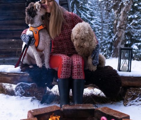 Woman sitting outdoors in winter with two Lagotto Romagnolo dogs, showcasing their affectionate temperament and curly coats.